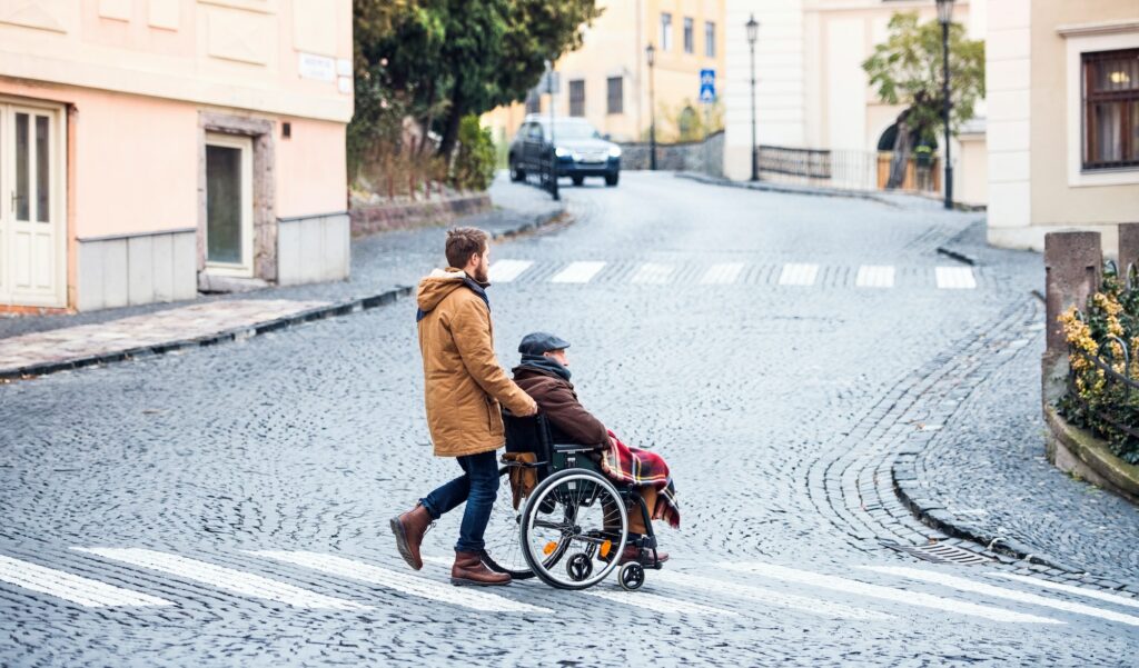 Senior father in wheelchair and young son on a walk.