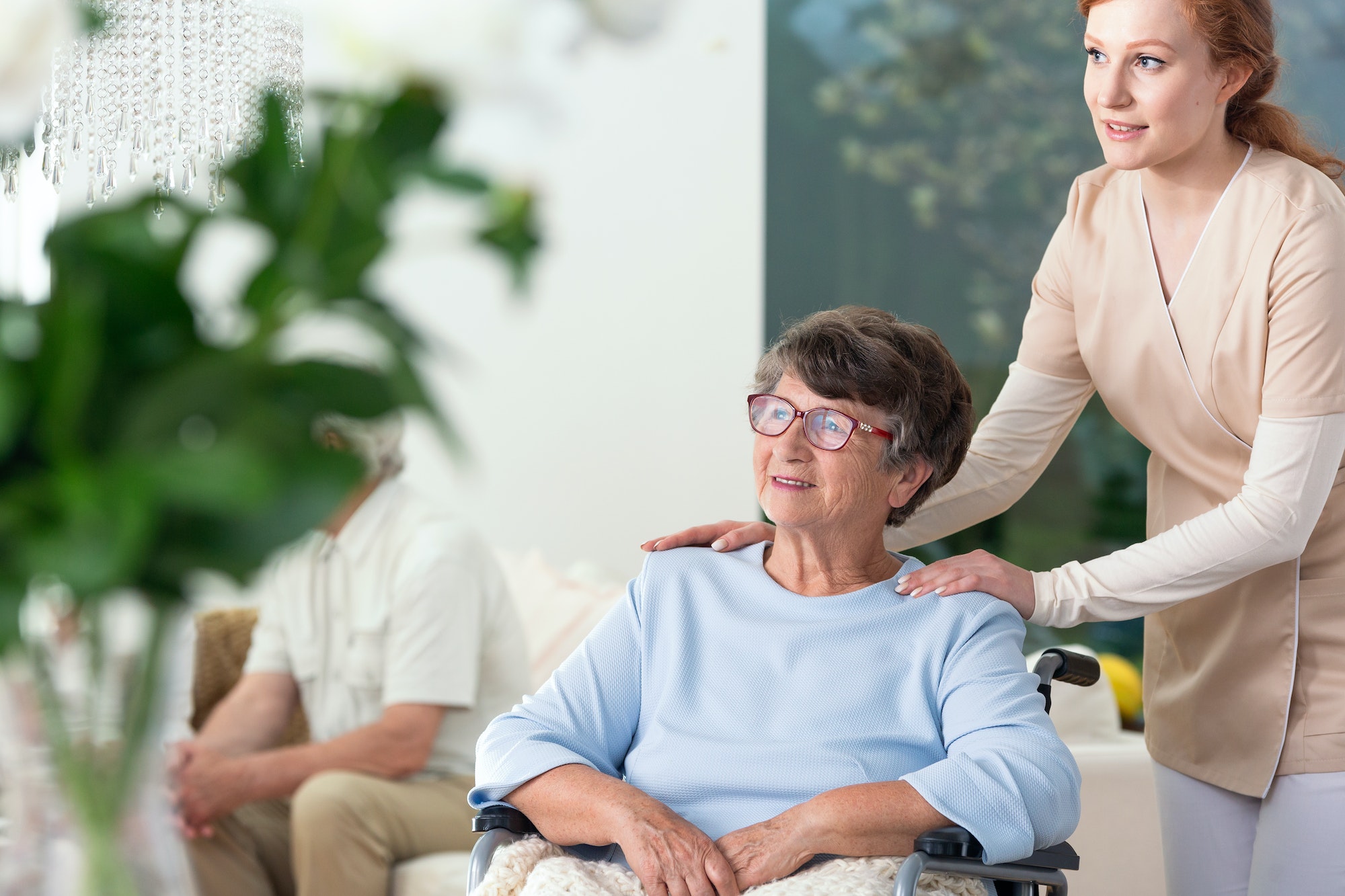 Caregiver taking care of disabled elderly woman in a wheelchair